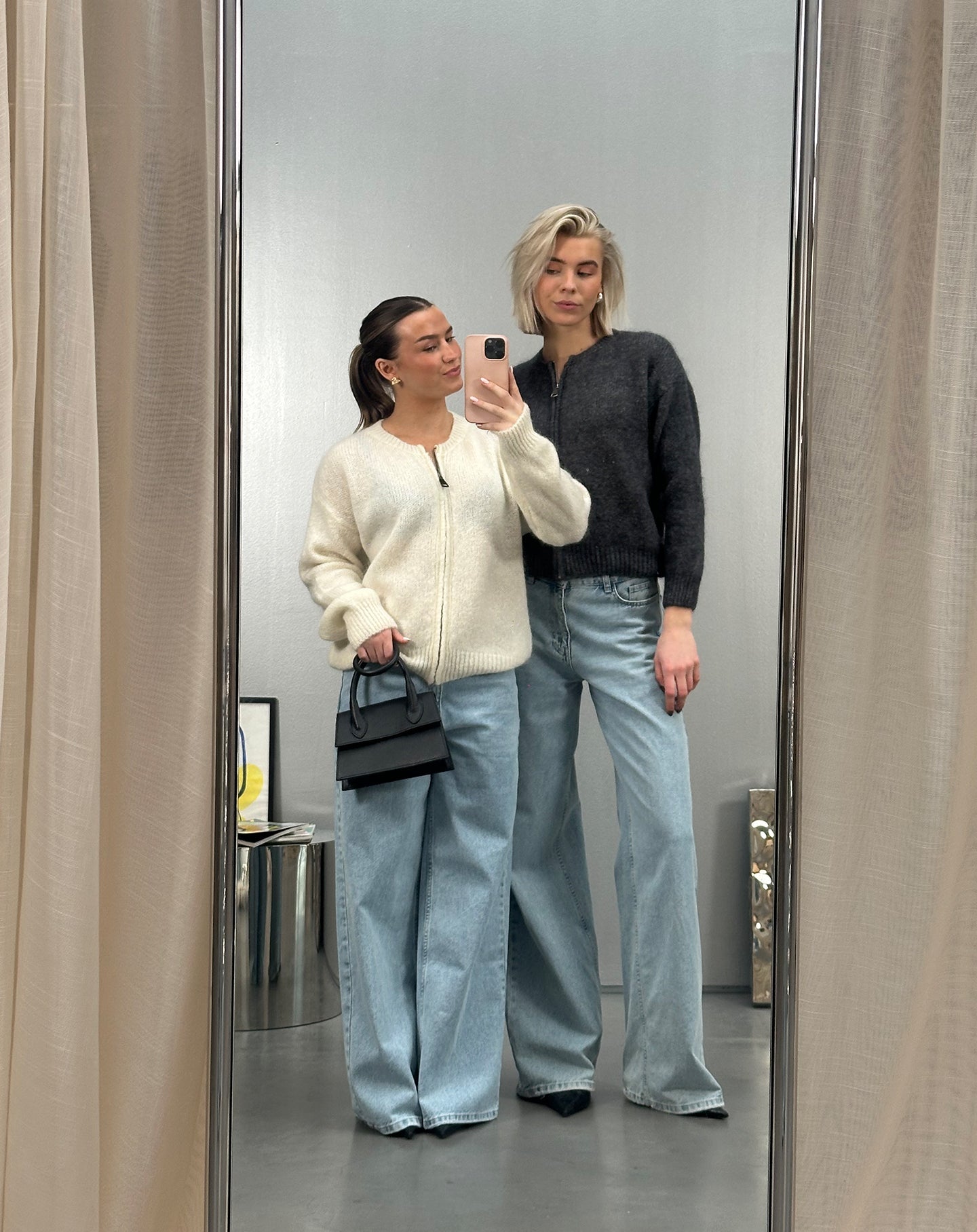 Twee dames in jeans, poserend voor de spiegel