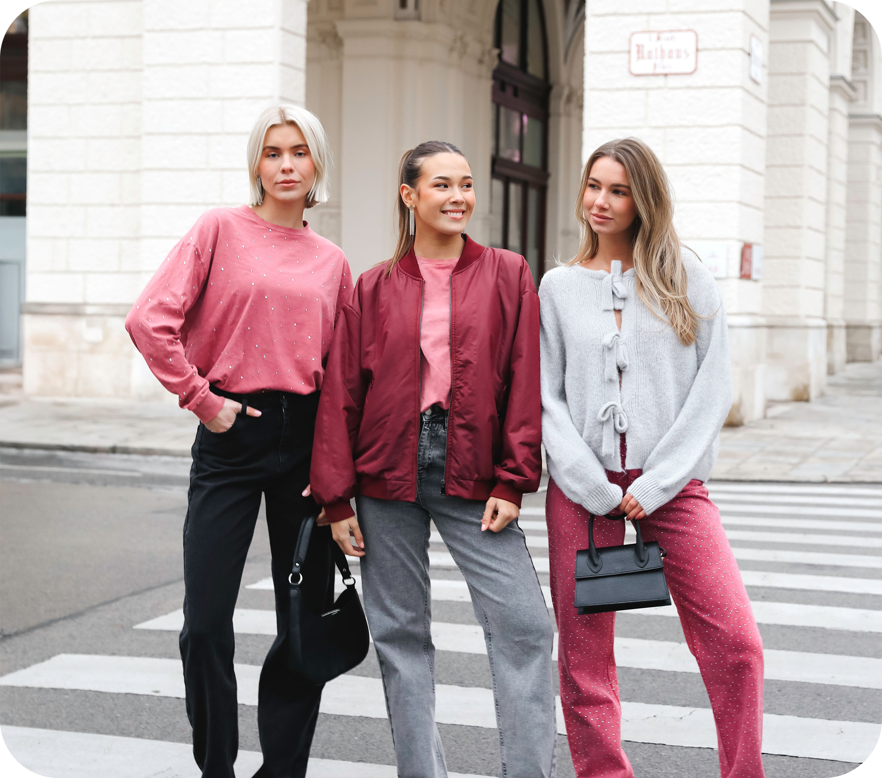 Drie dames in trendy kleding poserend op straat
