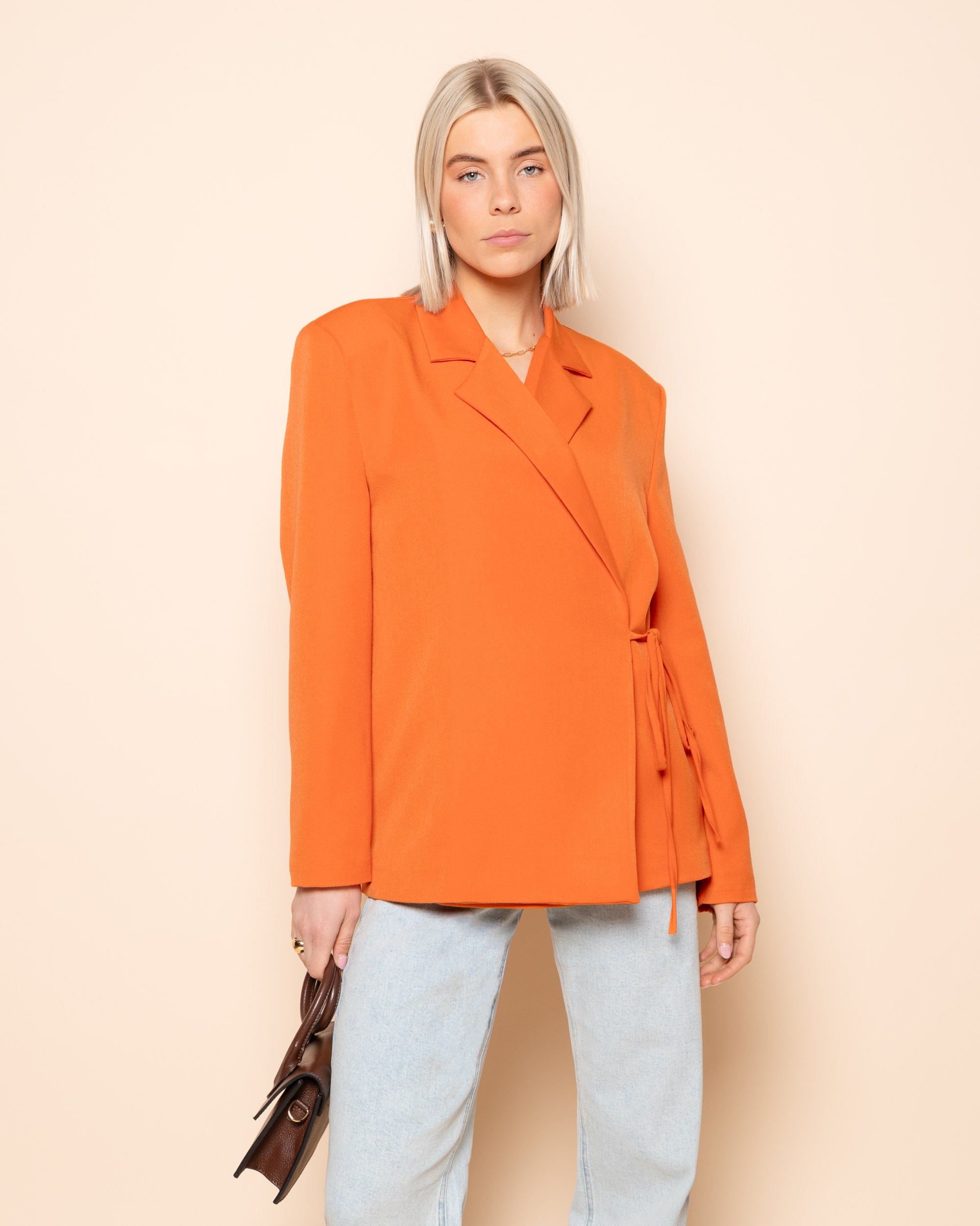 Model in de Iris wrap up blazer in de kleur oranje
