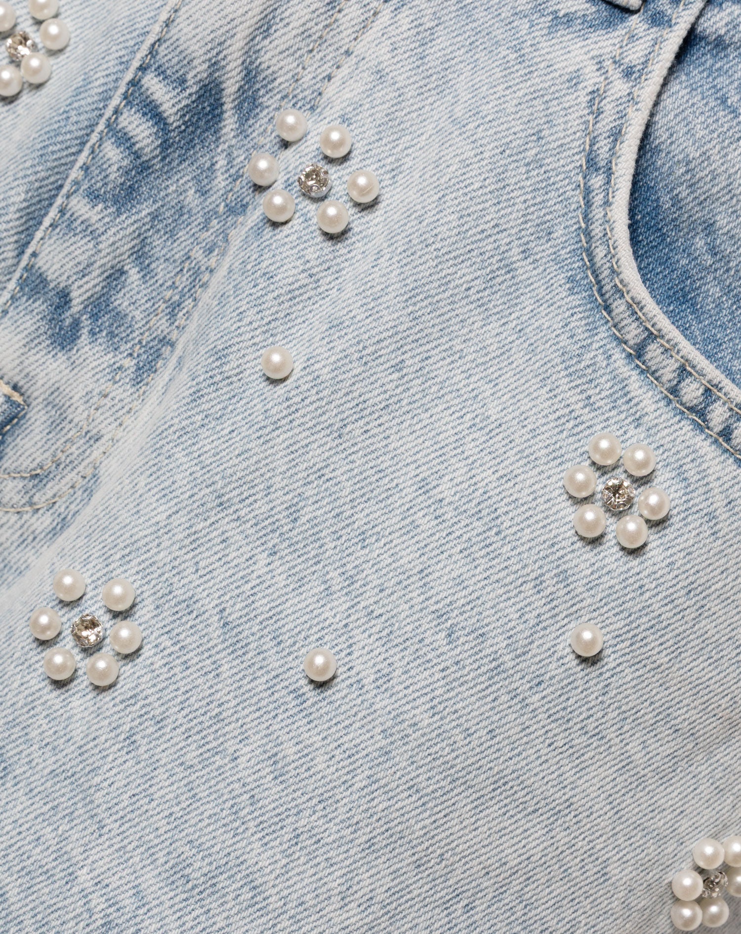 Parels in bloemvorm op een lichtblauwe spijkerbroek