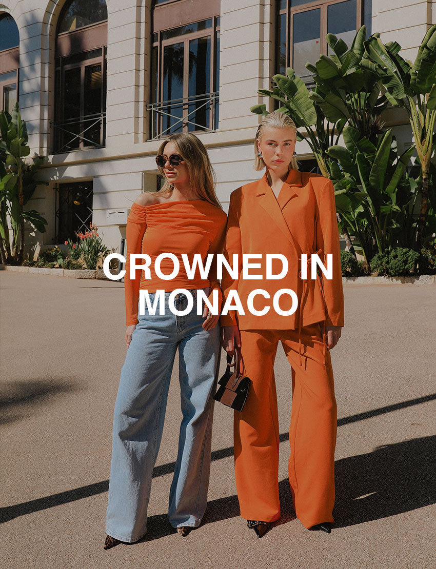 Twee vrouwen gekleed in oranje outfits, poserend voor een gebouw