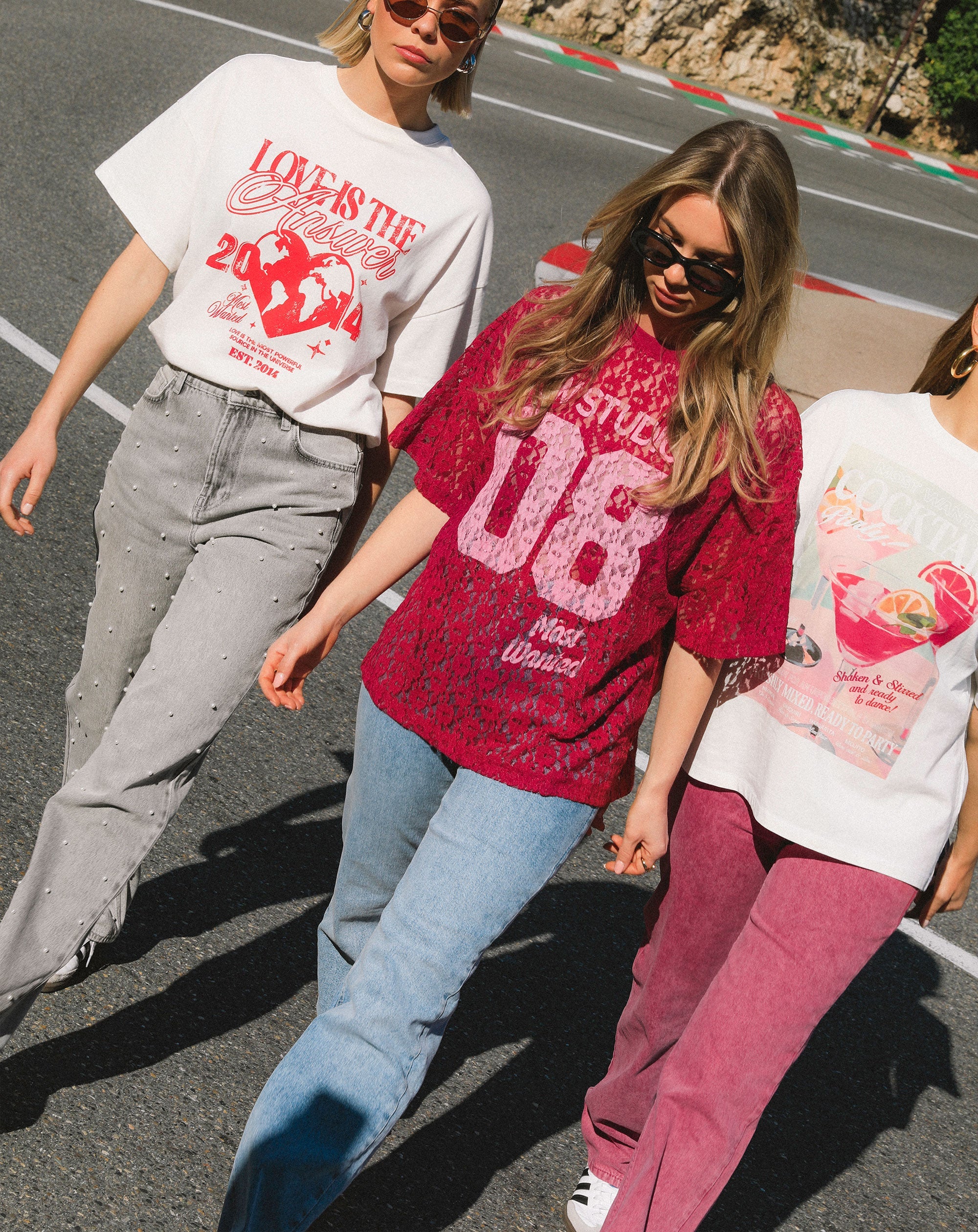 Drie dames in t-shirts met opdruk en jeans lopend over straat